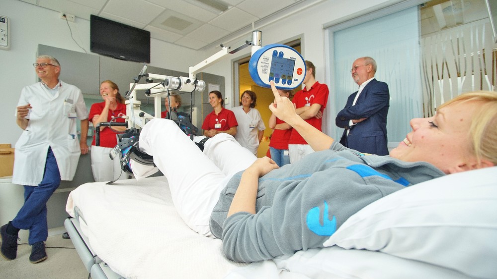 Cardioloog R. Vromans (links) heeft zojuist de elektrische bedfiets in ontvangst genomen van penningmeester Harrie van Boekel (rechts met bril). Foto: Gijs Hoogland.