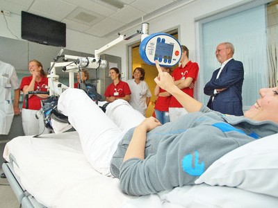 Cardioloog R. Vromans (links) heeft zojuist de elektrische bedfiets in ontvangst genomen van penningmeester Harrie van Boekel (rechts met bril). Foto: Gijs Hoogland.